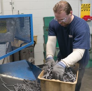 Employee wearing gloves and protective goggles as he sorts through materials