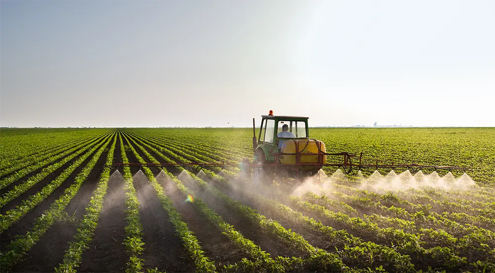 Tractor spraying pesticides on crops