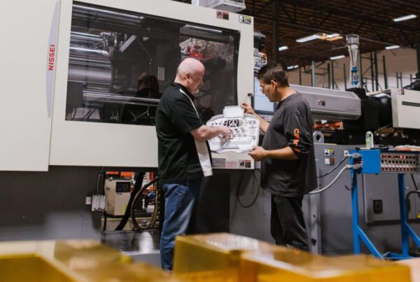 two men looking at plans for a rubber part discussing PFAS in front of a machine